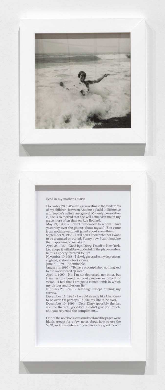 A square framed photograph of a woman in the ocean hanging over a framed text panel
