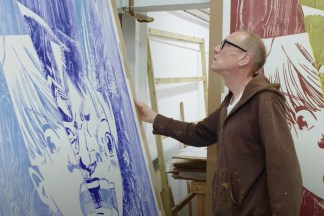 Video still of an artist looking at their work in their studio