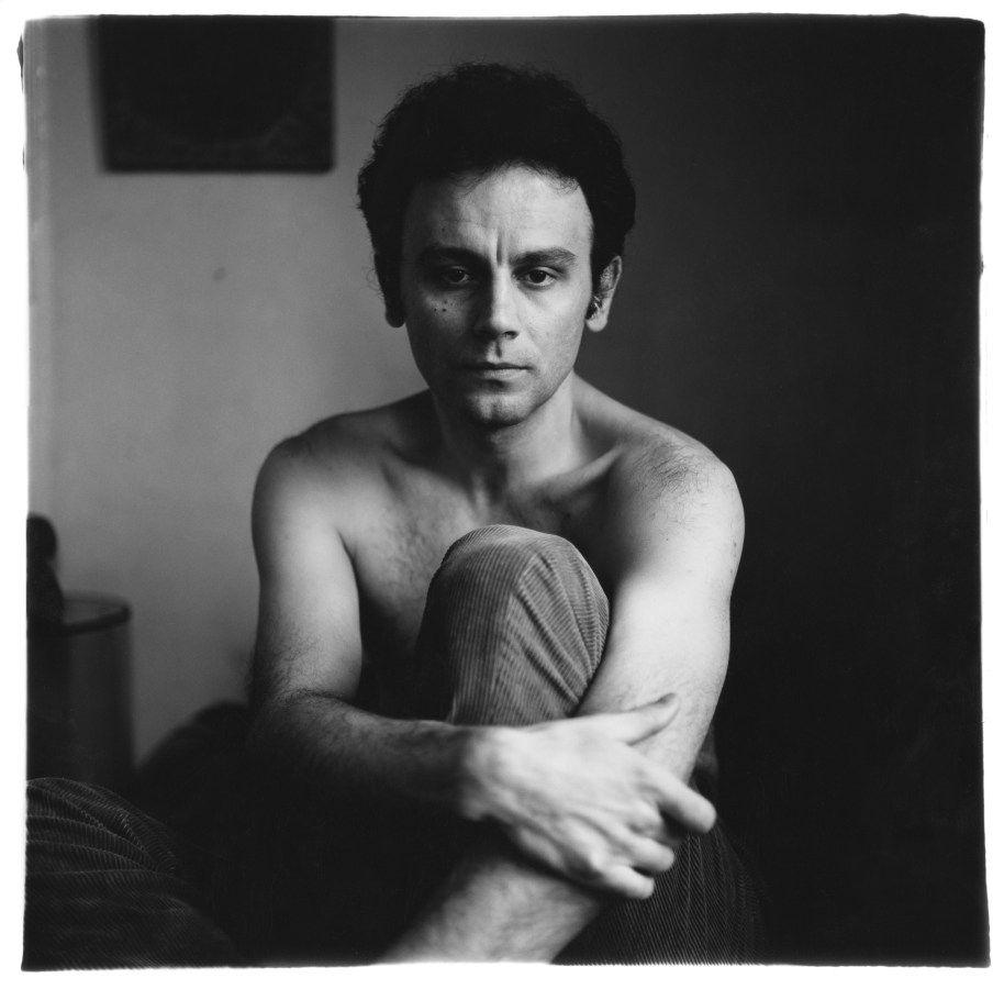 Black and white photograph of a seated figure shirtless