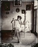 Black-and-white photograph of a woman sitting in a chair with her legs crossed