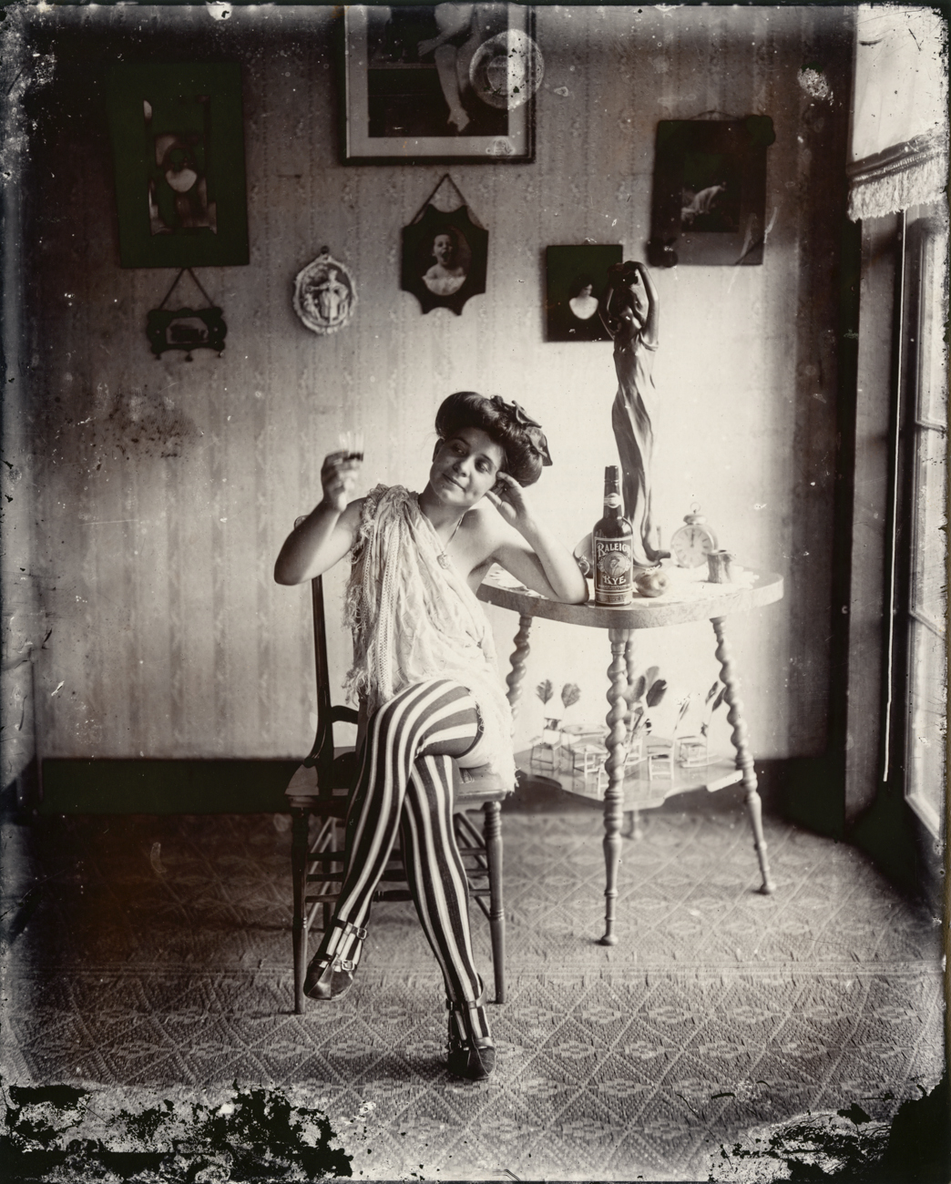Black-and-white photograph of a woman sitting in a chair with her legs crossed