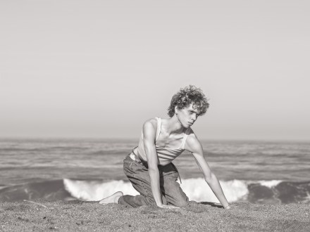 Black and white photograph of a figure on the beach on their hands and knees