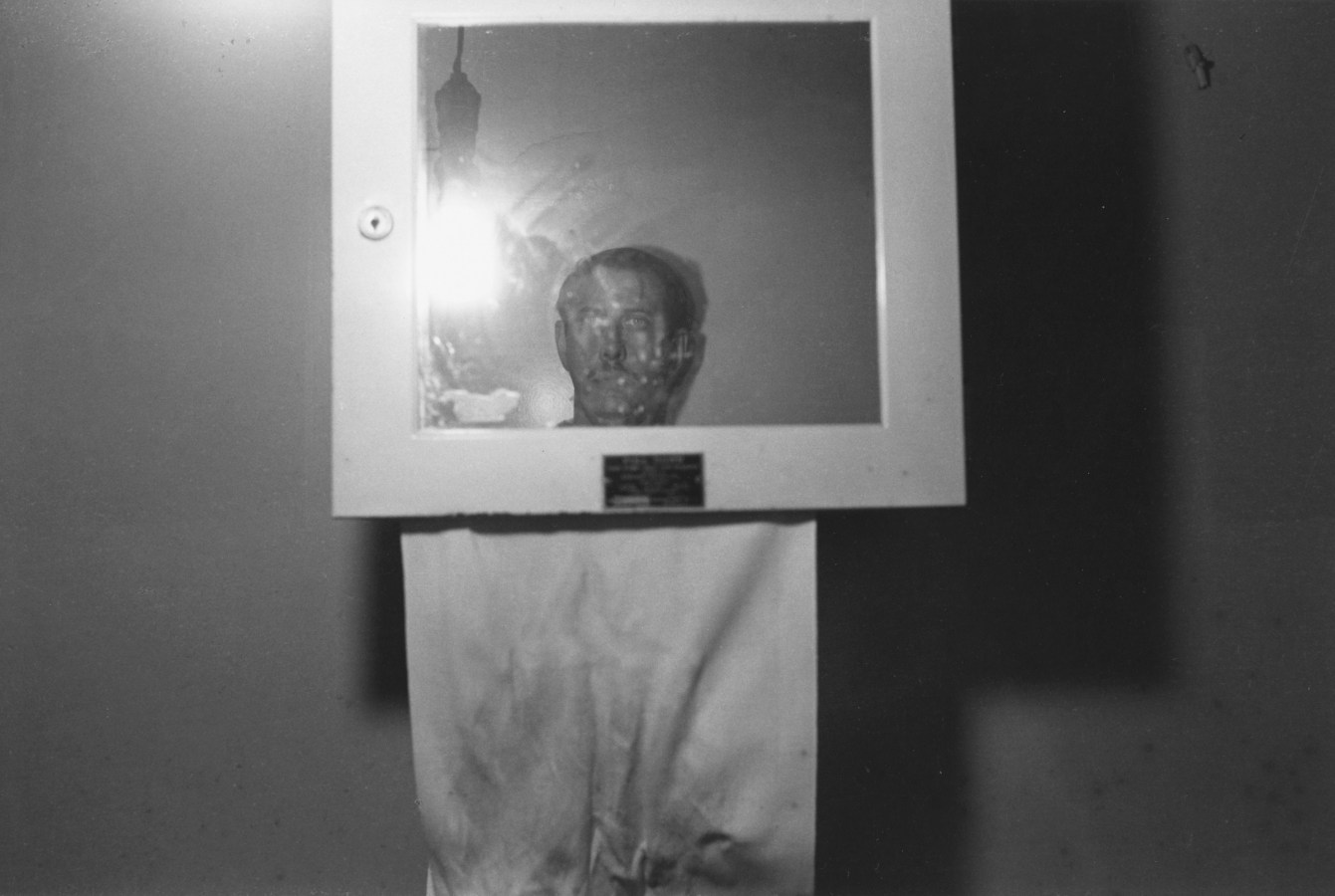 A black and white photograph of the artists reflection in a mirror.