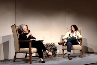 Image of two seated women holding microphones and talking