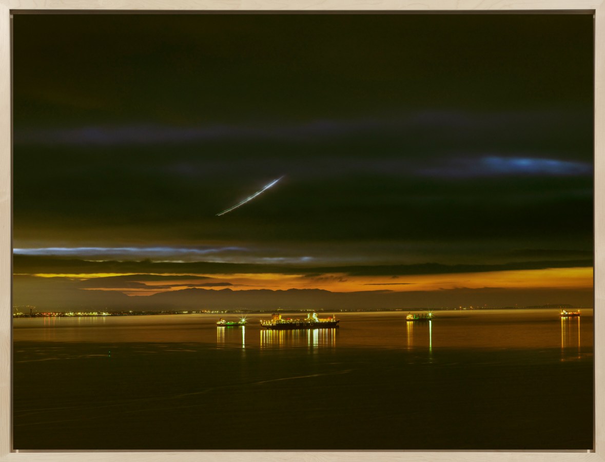 A framed color photograph depicting the San Francisco Bay with various cargo ships at sunset