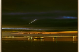 A framed color photograph depicting the San Francisco Bay with various cargo ships at sunset
