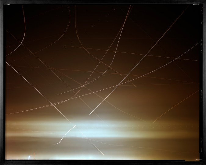Color image of a color photograph of along exposure depicting air traffic and Venus over san francisco framed in black