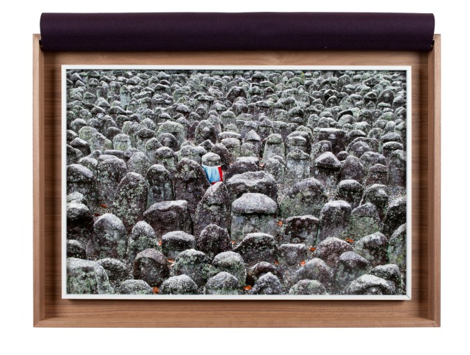 A framed photograph of a graveyard, with an apron around one stone, inside a wooden box