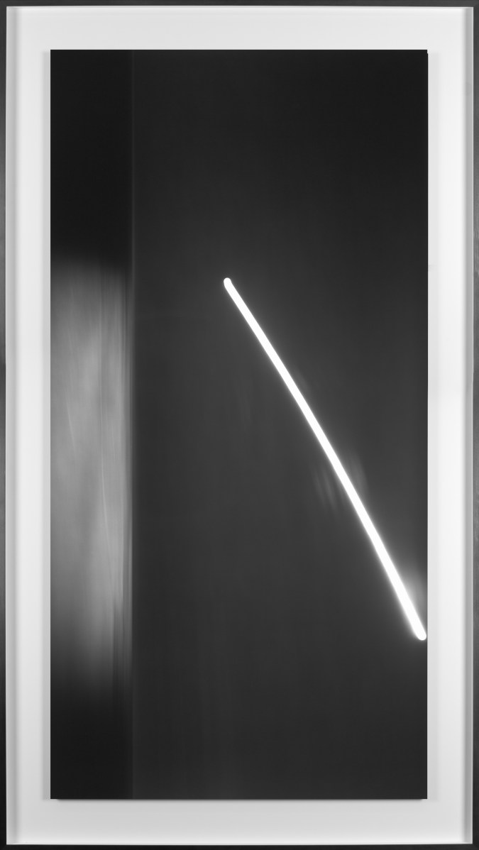 Black and white photograph of the ocean horizon at night with a long exposure of the moon framed in black