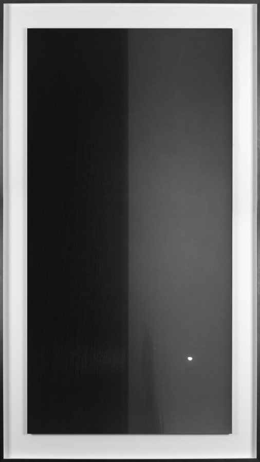 Black and white photograph of the ocean horizon with the moon above the horizon line framed in black