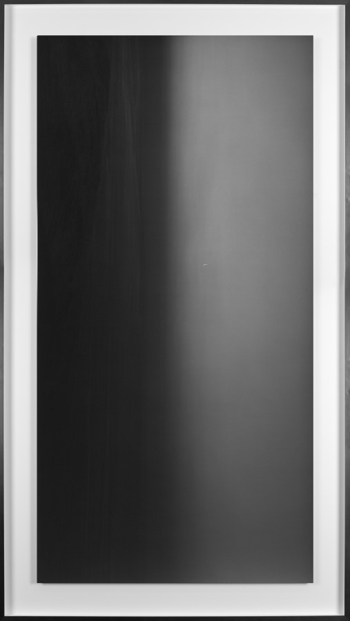Black and white photograph of the ocean horizon with the moon above the horizon line framed in black