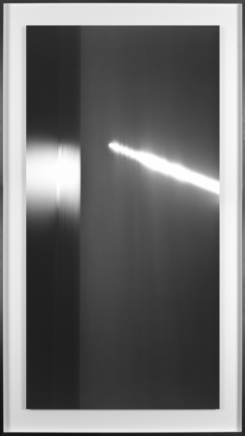 Black and white photograph of the ocean horizon at night with a long exposure of the moon framed in black