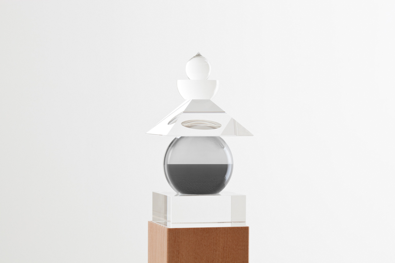 Glass sculpture of stacked geometric shapes with a black-and-white photo of a seascape inserted in the central orb