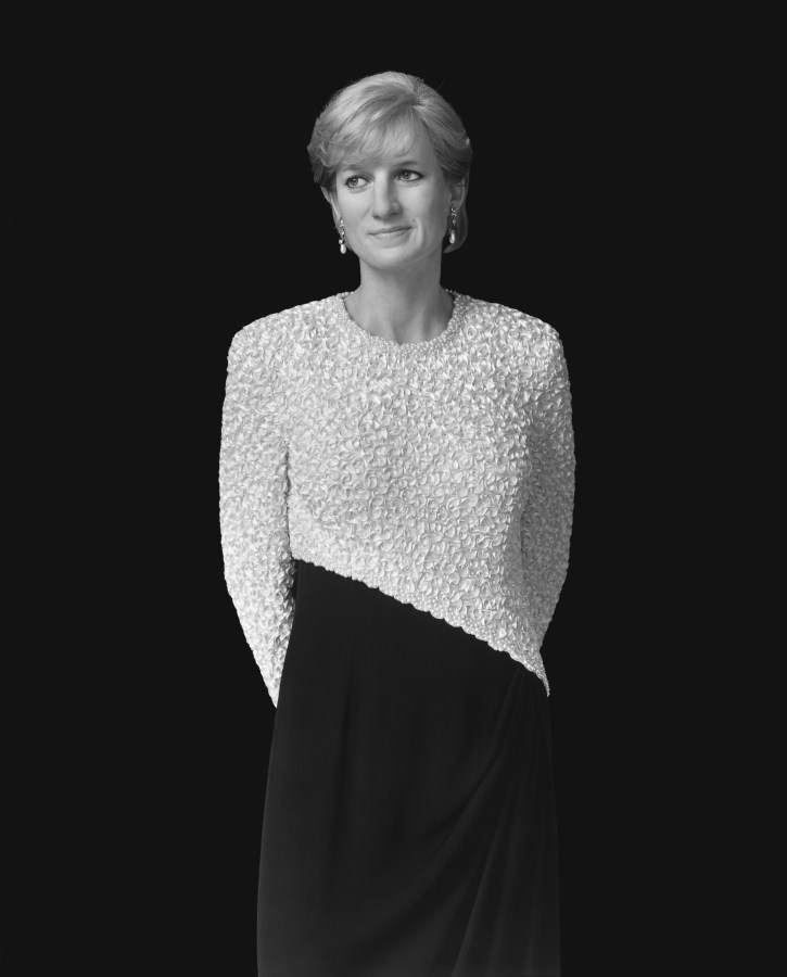 Black-and-white frontal portrait of a wax figure of a woman in an asymmetrically patterned dress with her hands behind her back
