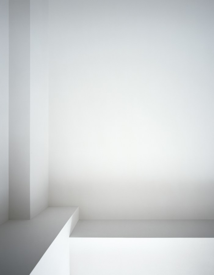 Photograph of a white ceiling with linear beams next to a window cut-out in varying shades of gray